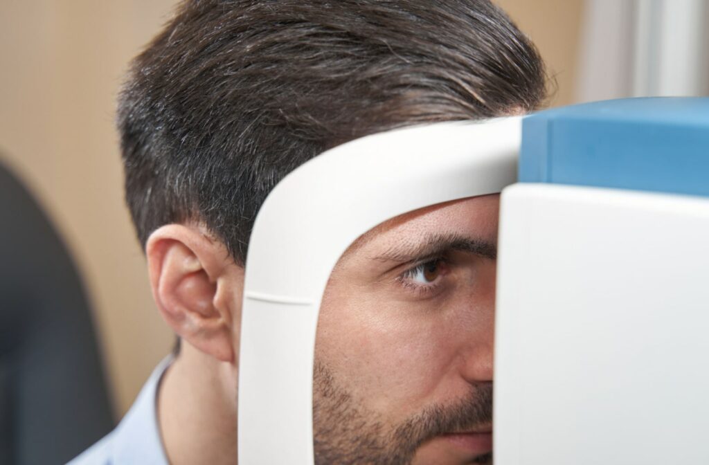 A close up of an adult male is looking into autorefractor during eye exam