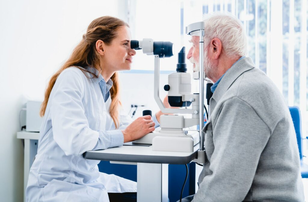 A female optometrist uses a slit lamp to examine an older male patient's eyes