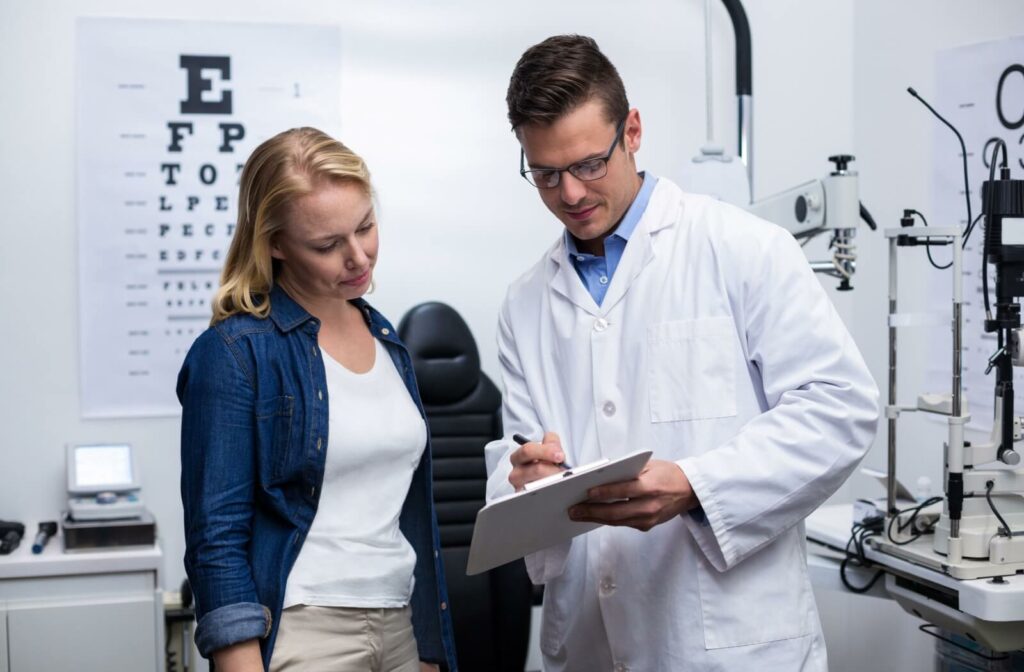 An eye doctor with a patient looking at a chart and discussing her medical history.