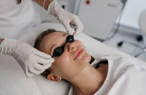 An eye doctor placing protective eyewear over a woman's face before starting IPL therapy.