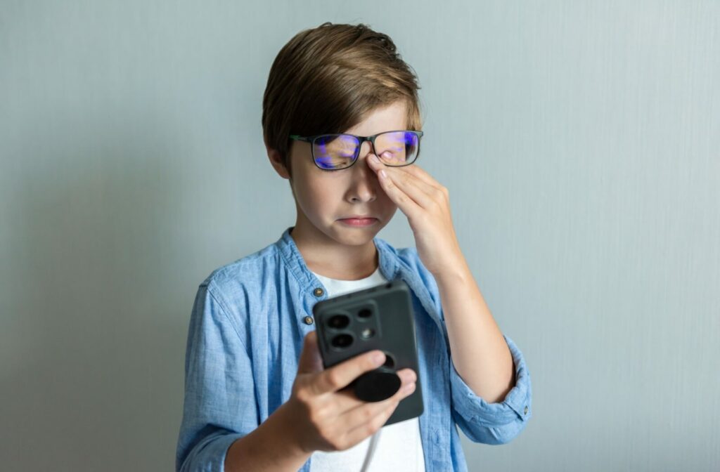 Young boy rubs at his eyes due to astigmatism fatigue.