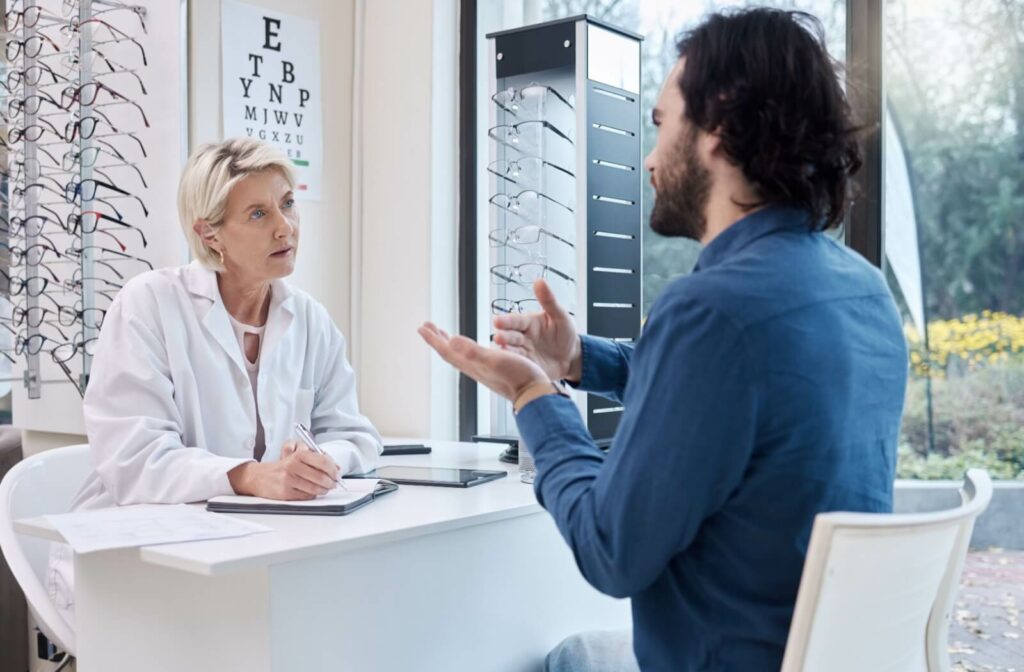 An optometrist listening and taking notes while their patient describes their symptoms after waking up with dry eyes.