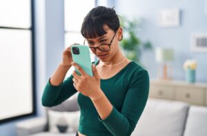A person lowers their glasses and squints at their phone.