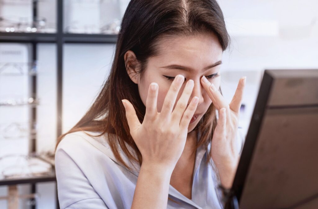 A woman rubbing her eyes appearing to experience eye discomfort.