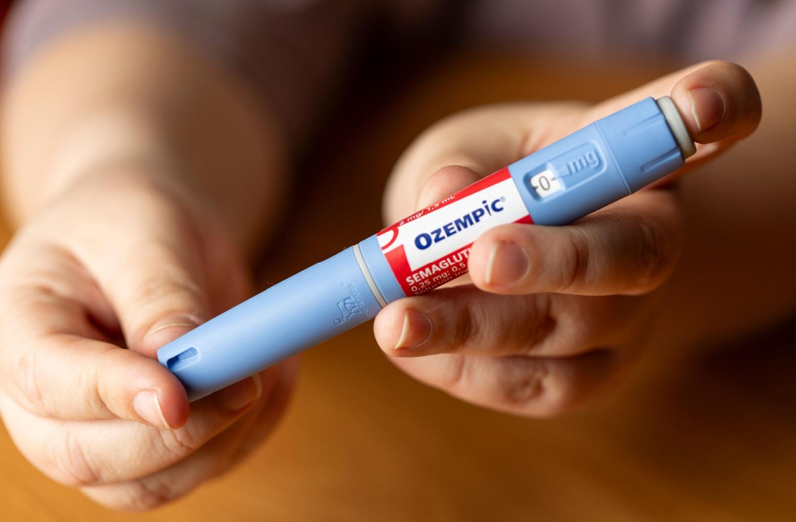 Person holding an Ozempic injection pen, a medication commonly used for diabetes and weight management